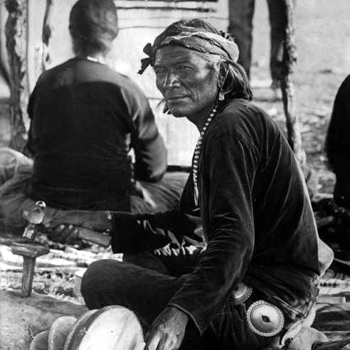 First Phase Navajo Silversmith Wearing a Concho Belt and Naja Pendant Necklace Pounding Sterling Silver with a Hammer into Navajo Jewelry