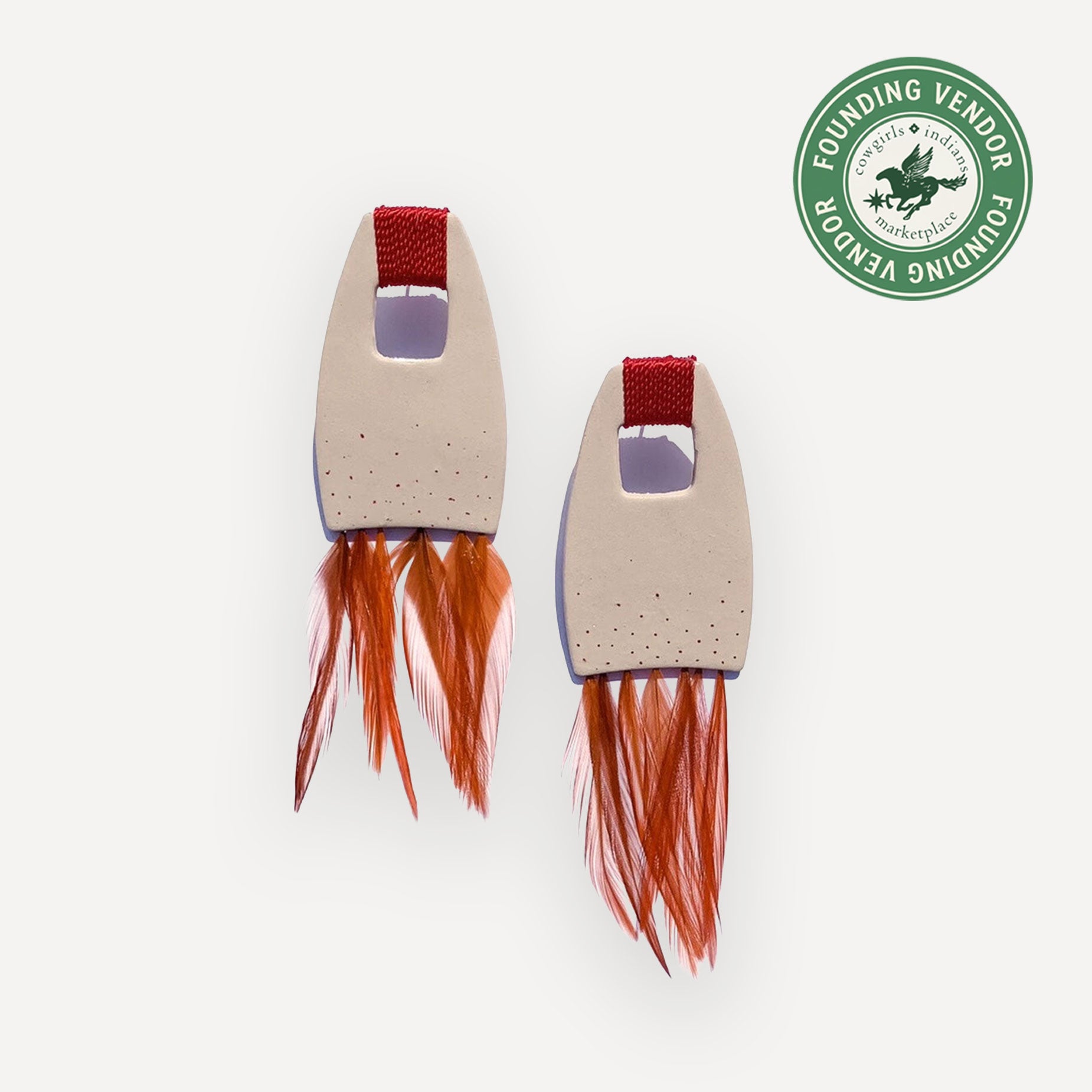 beige and red feather earrings on white background