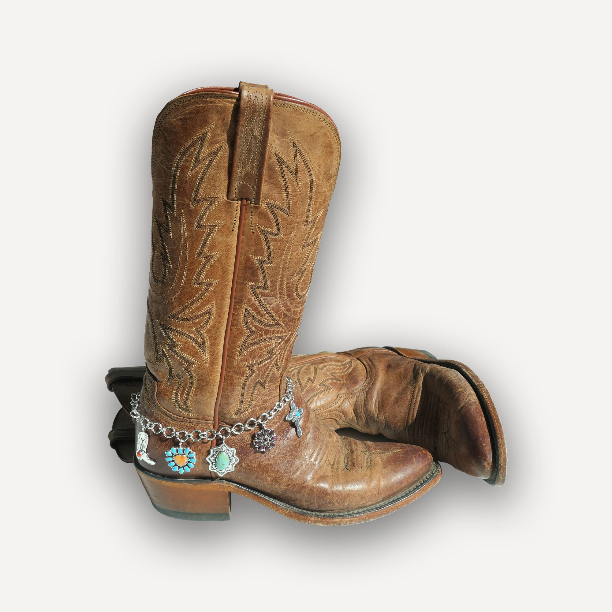 Brown Lucchese cowboy boot with boot jewelry on a white background