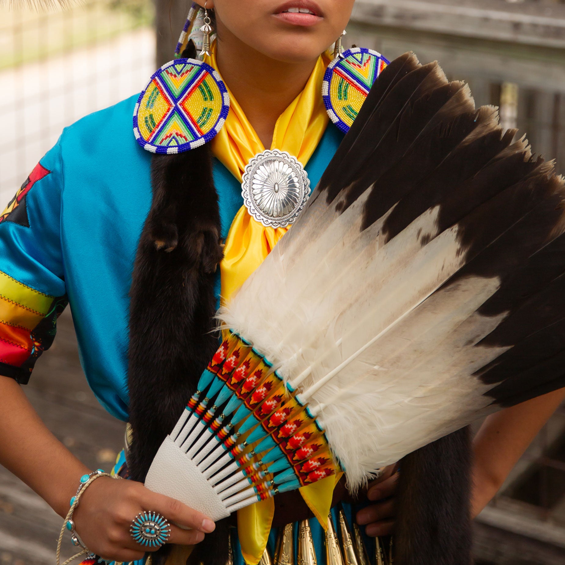 Person wearing traditional Native American attire with feathers and colorful clothing.