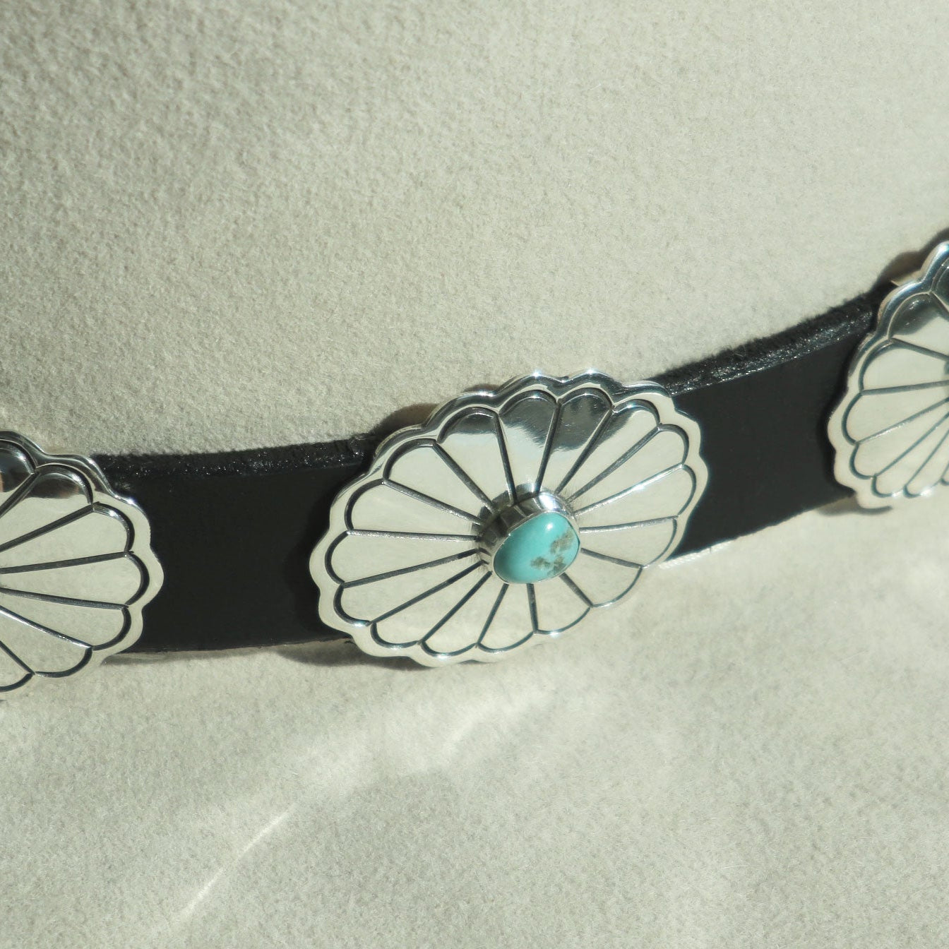 close-up: Intricate stampwork and turquoise on silver conchos attached to the Rough Rider leather band.