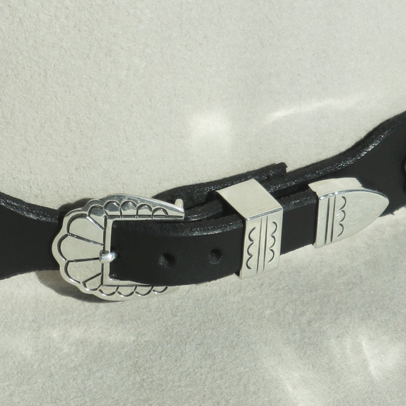 Detail: Rough Rider hatband's stamped sterling silver buckle, keeper, and tip on the leather strap.
