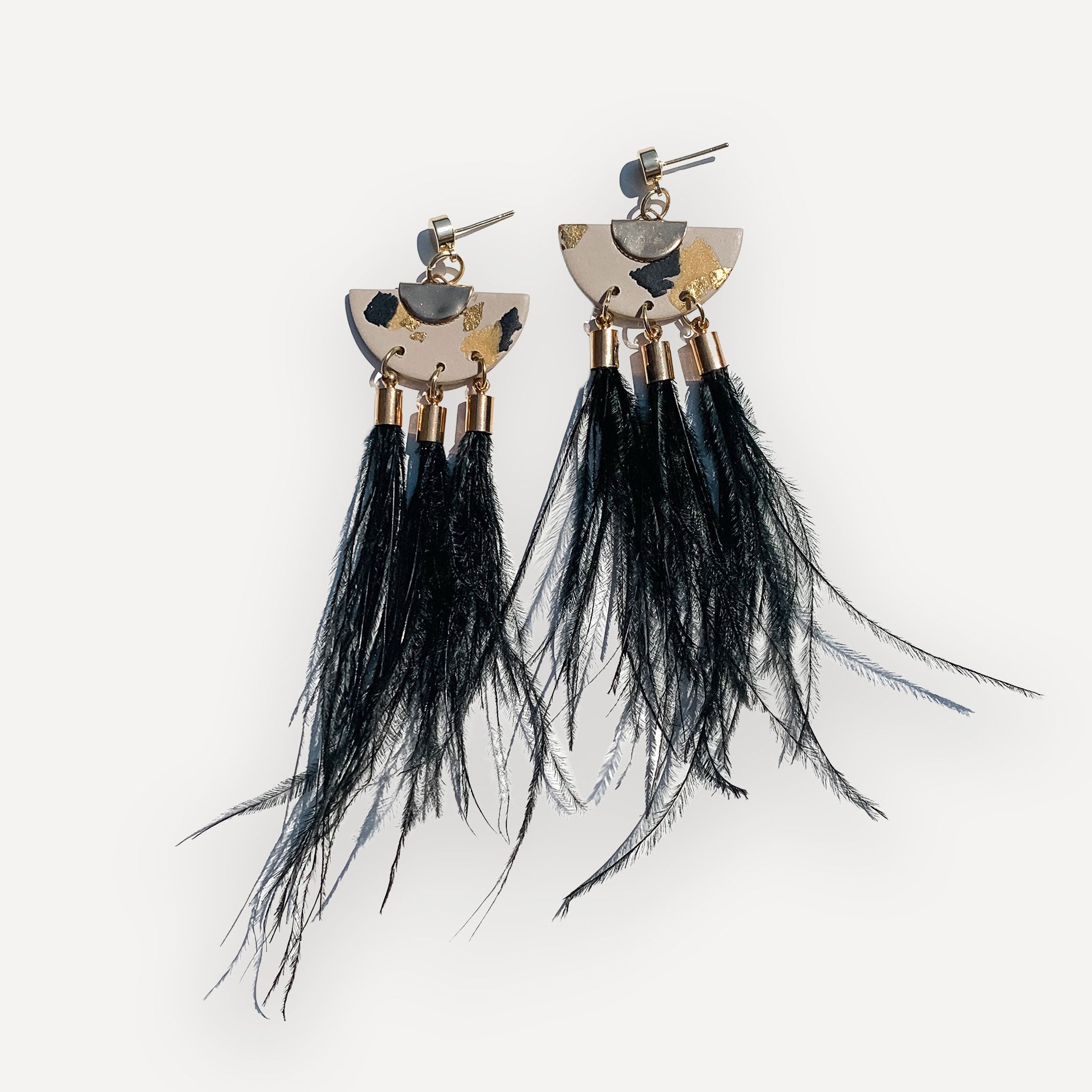 Pair of earrings with black ostrich feather tassels on a white background