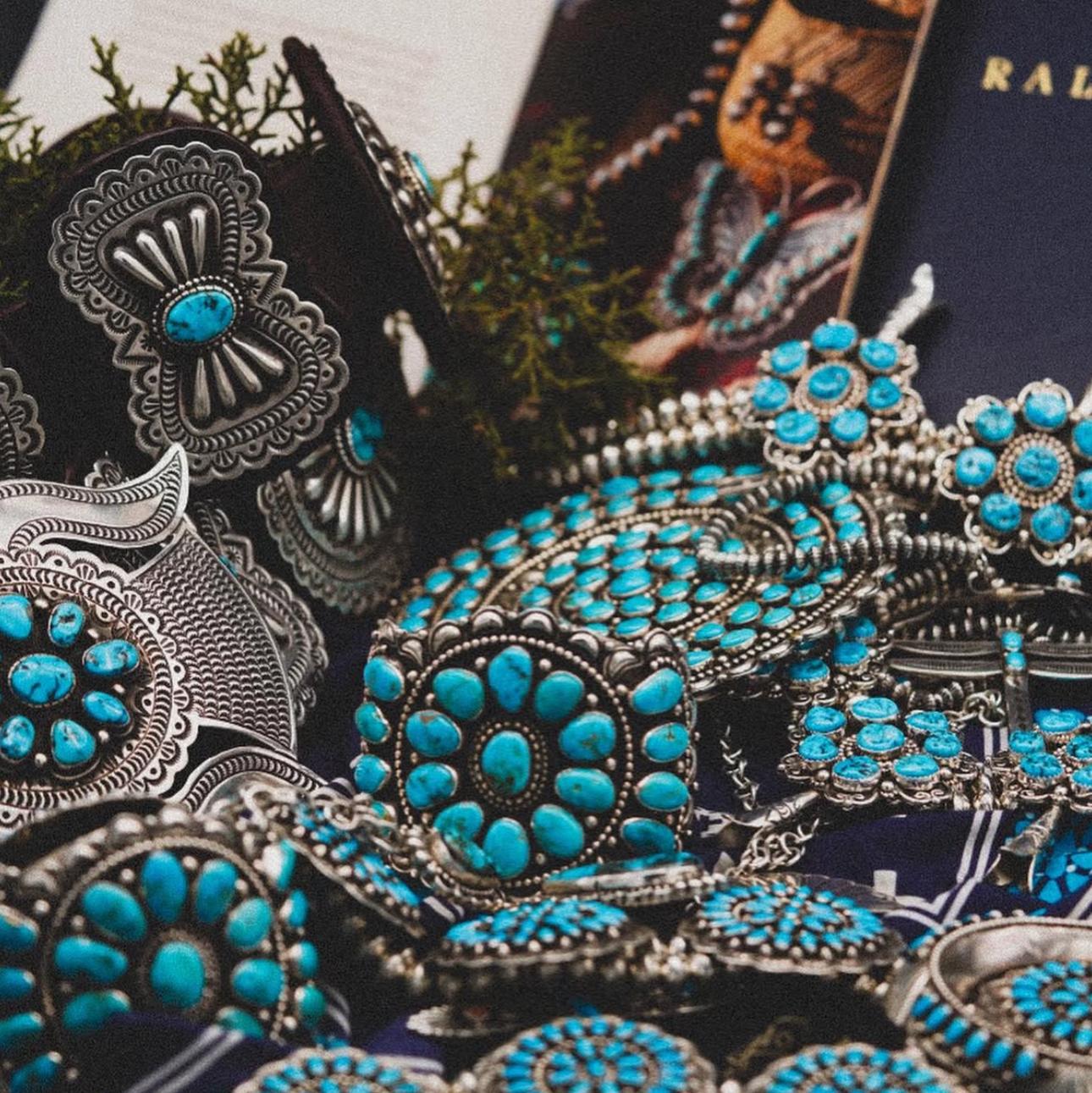 Close-up of decorative brooches, squash blossoms, belt, cuffs with turquoise stones on a dark background
