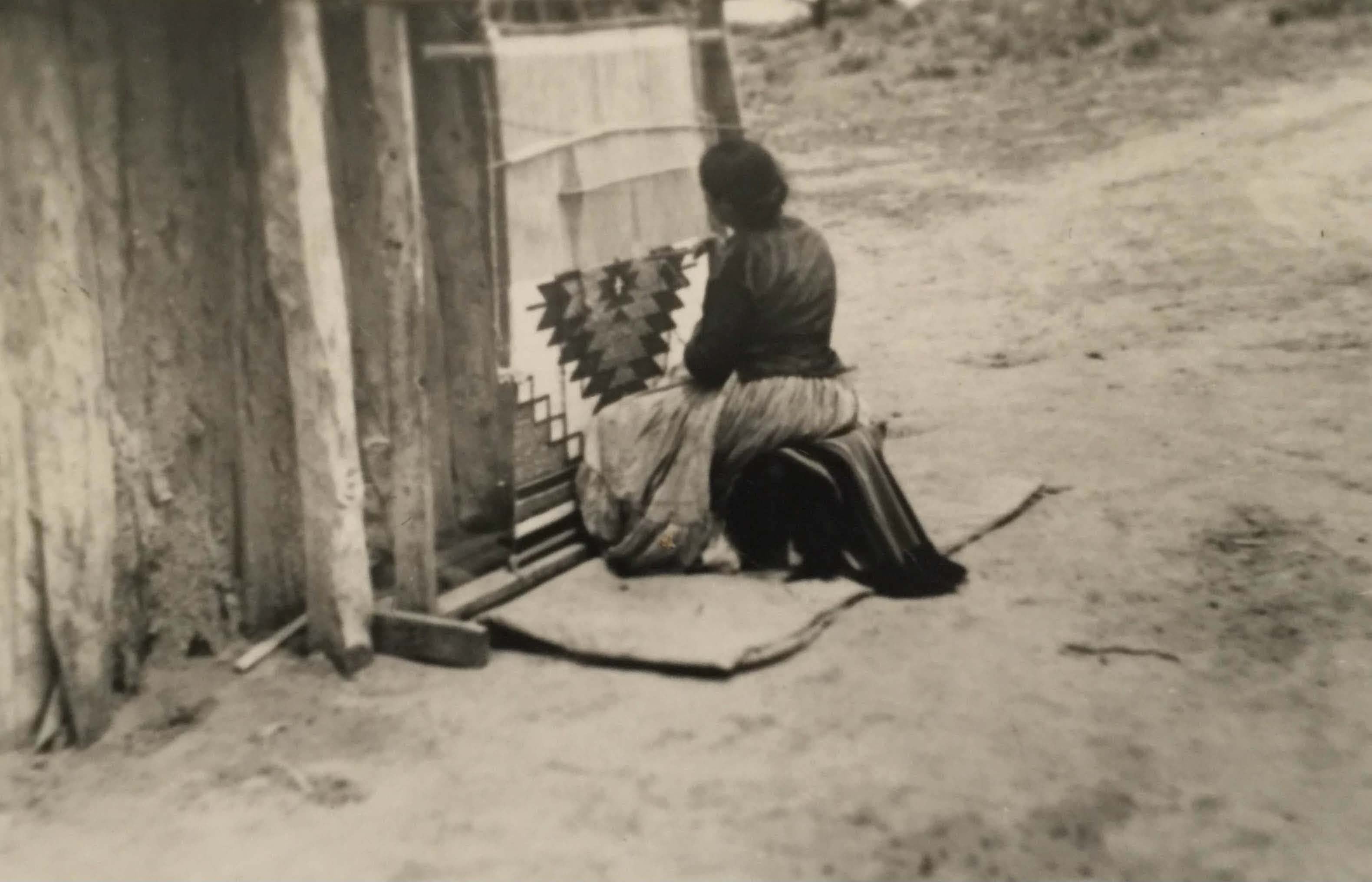 Tessie Skeet weaving a Navajo Rug beside a hogan on a Navajo Loom.