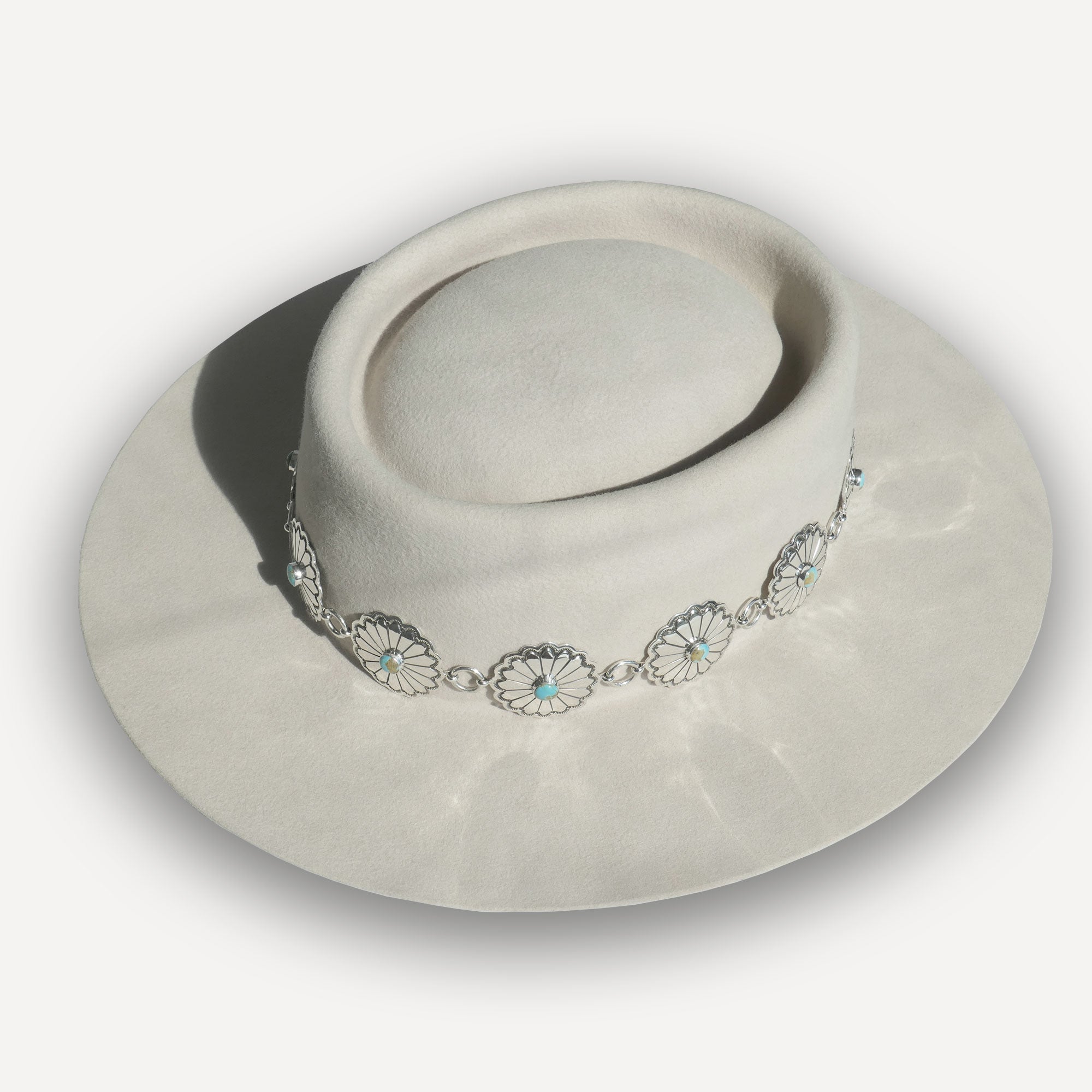 Sterling silver Nizhoni Navajo concho link hatband with turquoise stones shown on a light felt hat by Montana Territory Hat Company.