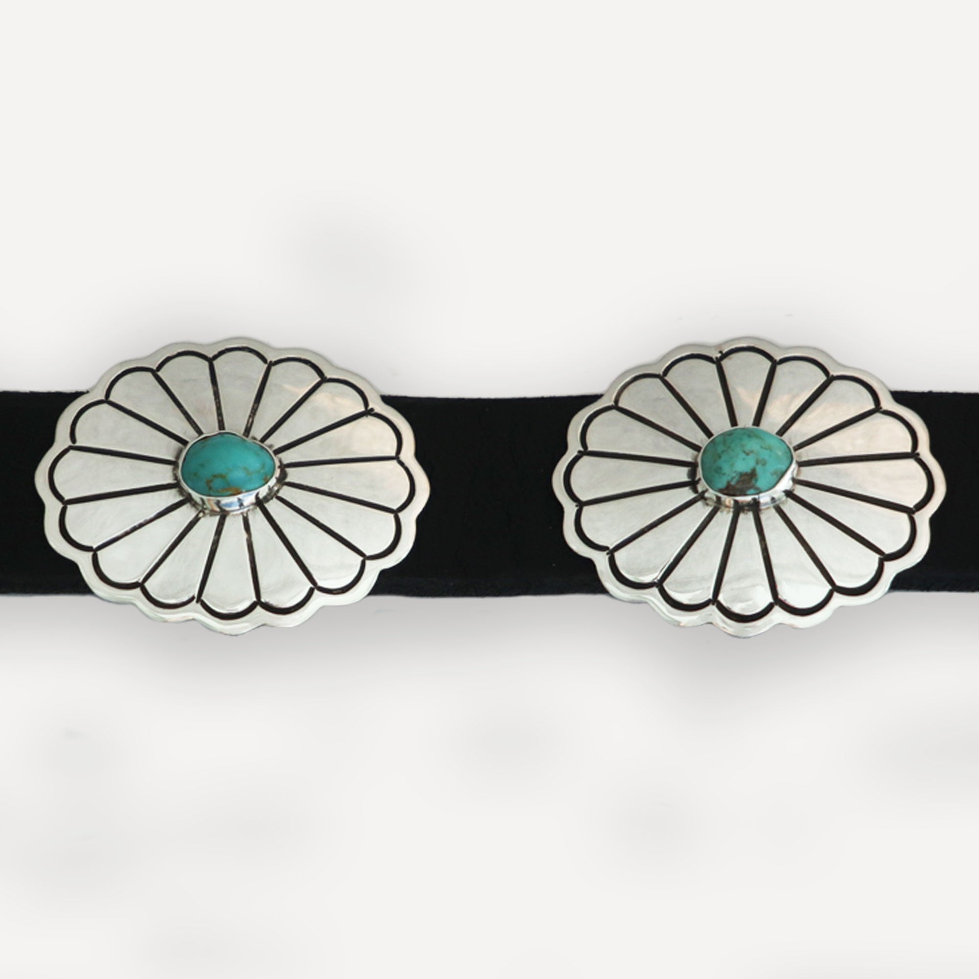 Close-up black leather and sterling silver conchos with kingman turquoise cabochons on white background