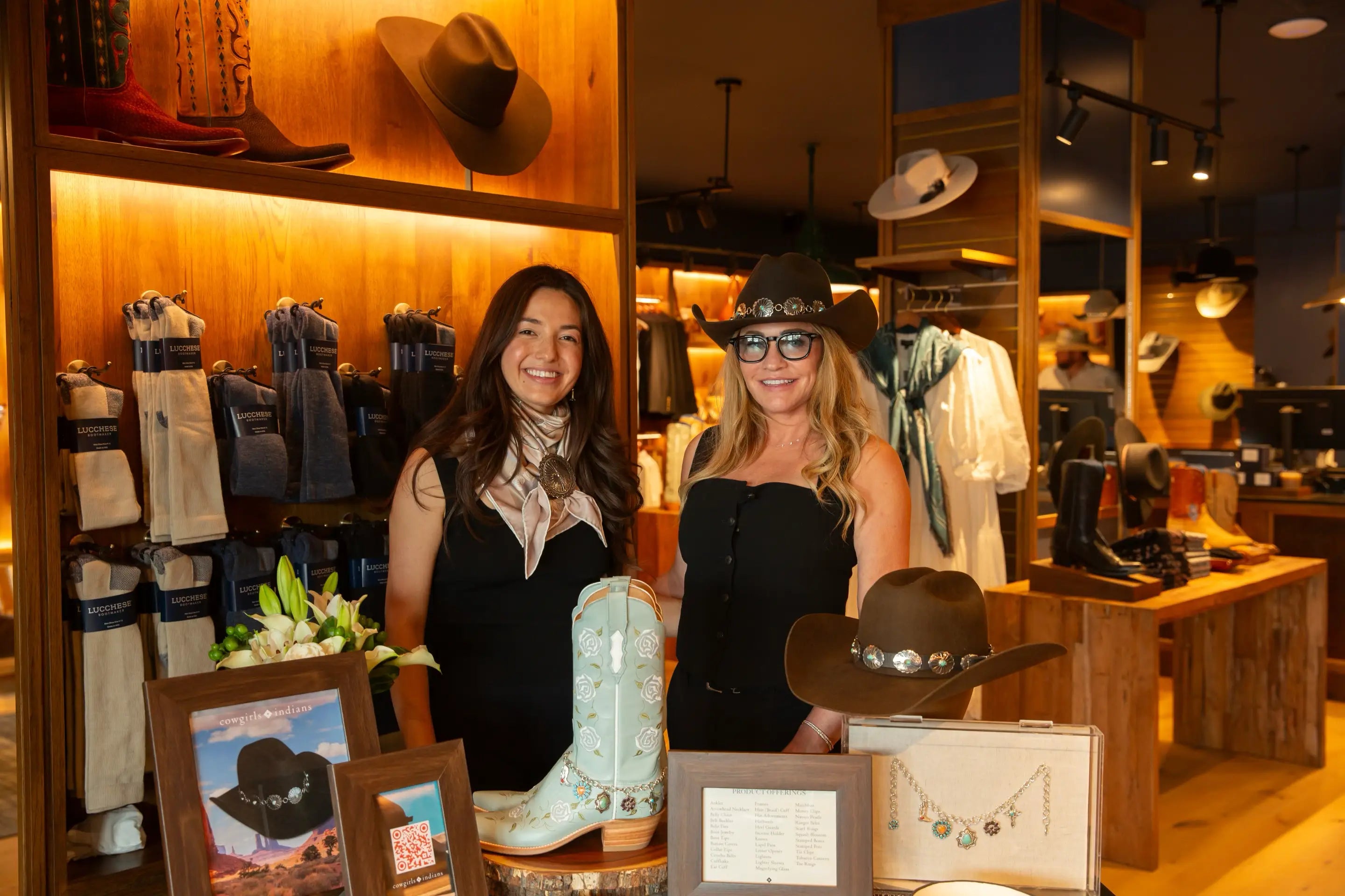 Two women in a lucchese store with cowboy hats and boots on display.