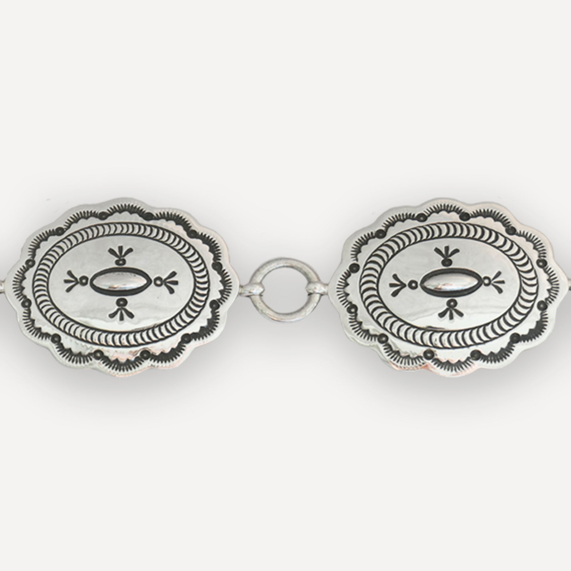Up-close Navajo Concho with black handstamped accents on white background