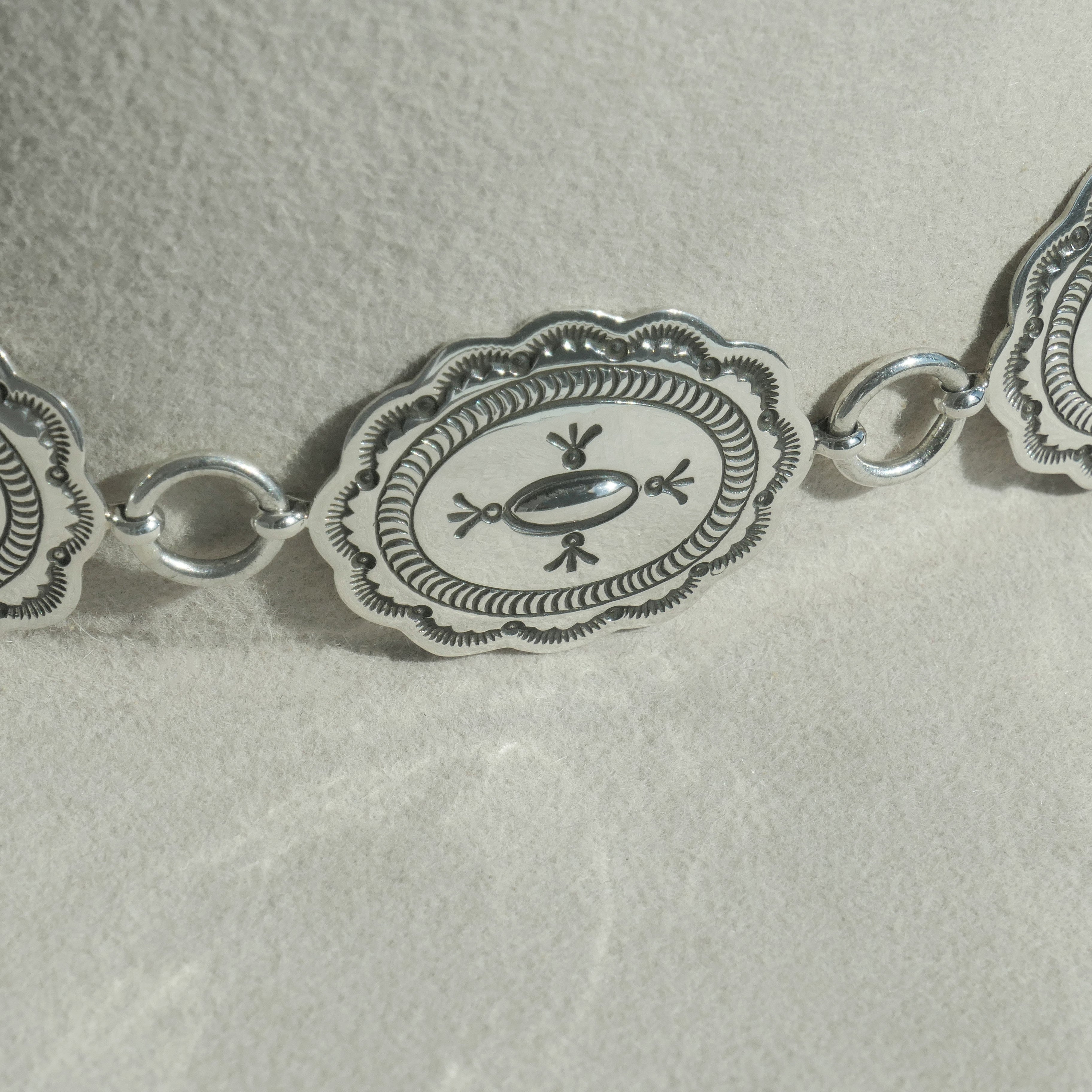 Detailed close-up of the Texas Flood hatband: Linked oval, sterling conchos feature scalloped edges, a stamped border, and a central stamped pattern against the hat's fabric.