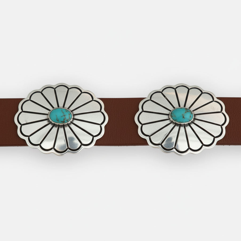 Close-up brown leather and sterling silver conchos with kingman turquoise cabochons on white background