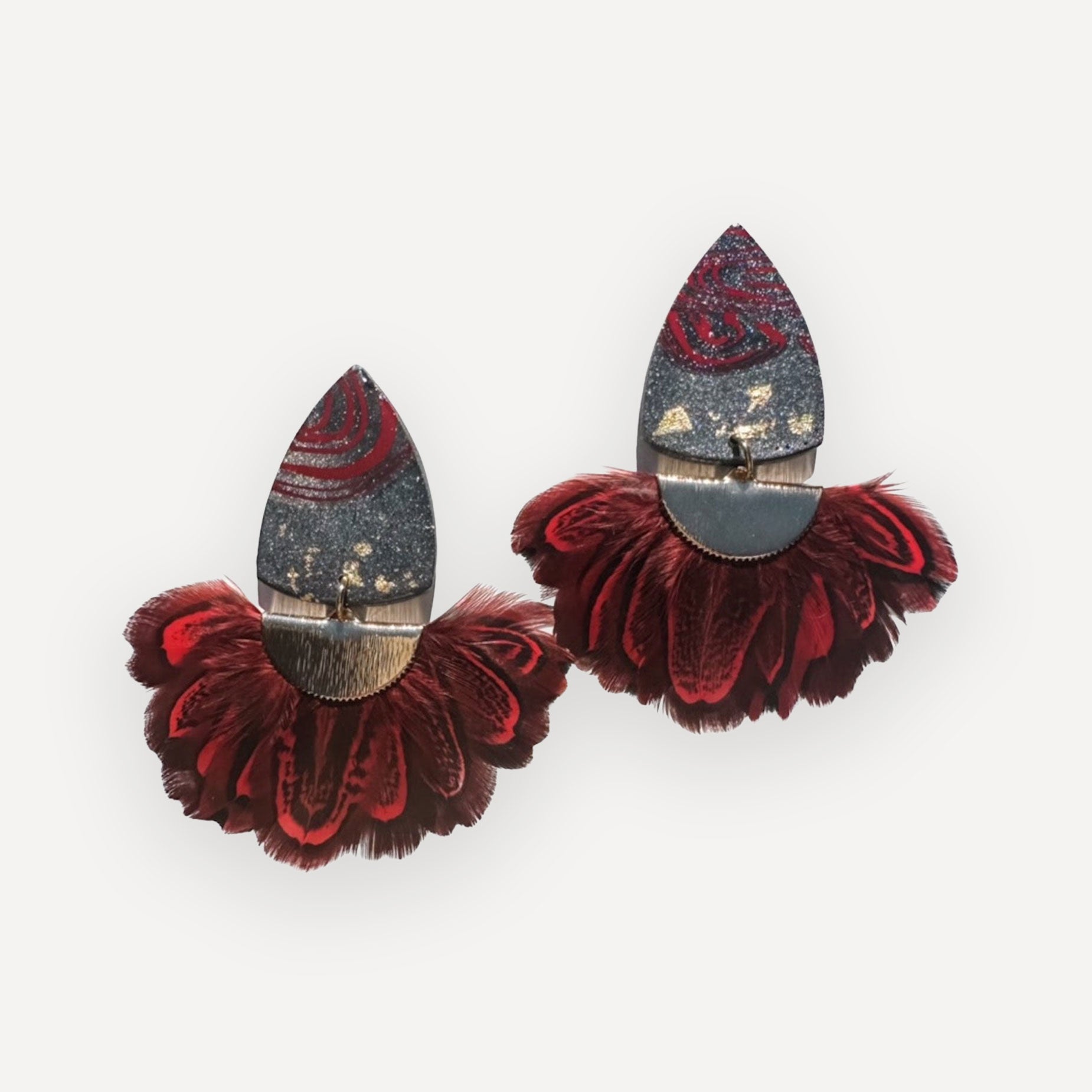 Pair of decorative earrings with red and gold details on a white background