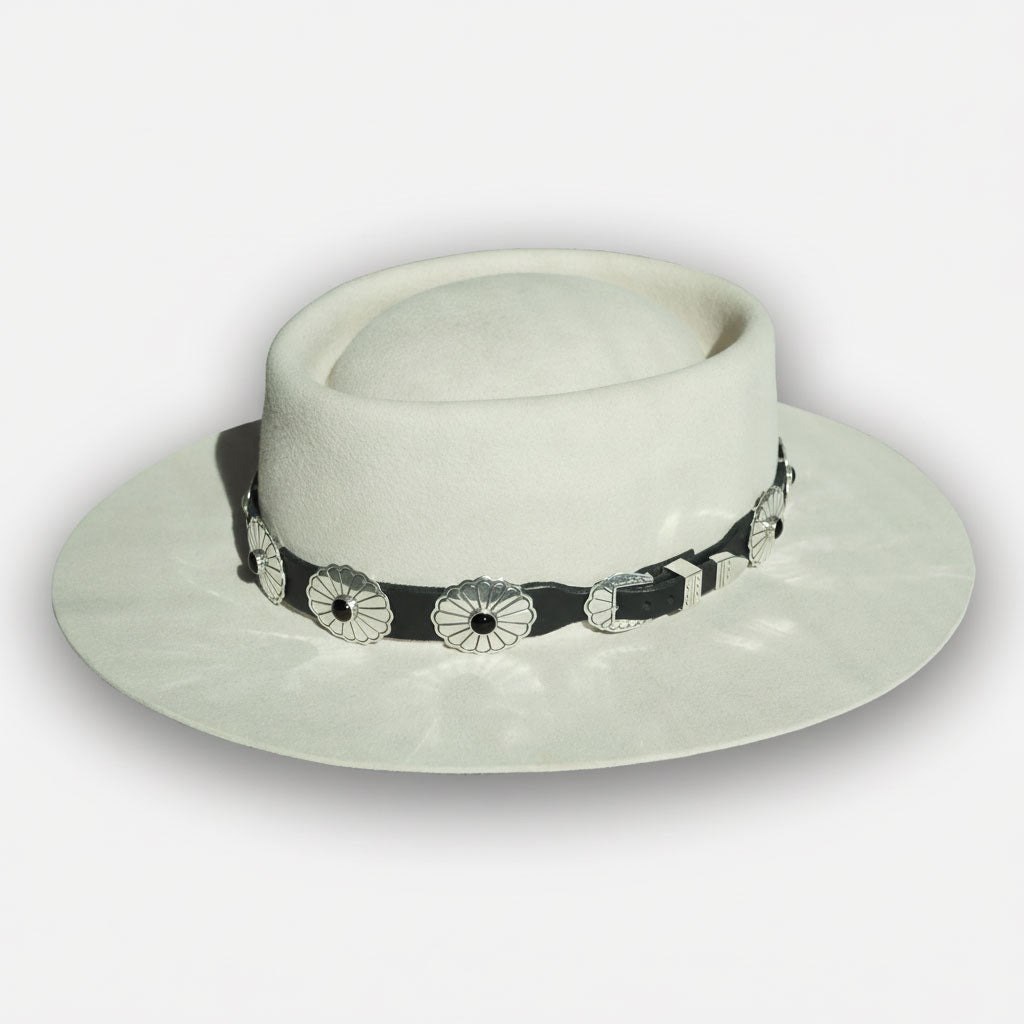 Wide brimmed hat adorned with hat band accessories in sterling silver, black leather, and black onyx, on a white background