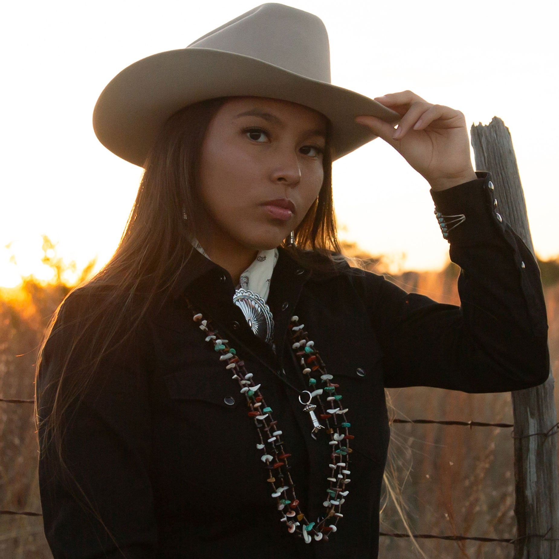 Girl wearing a light felt hat with a sterling silver concho scarf ring on a sunset background. 