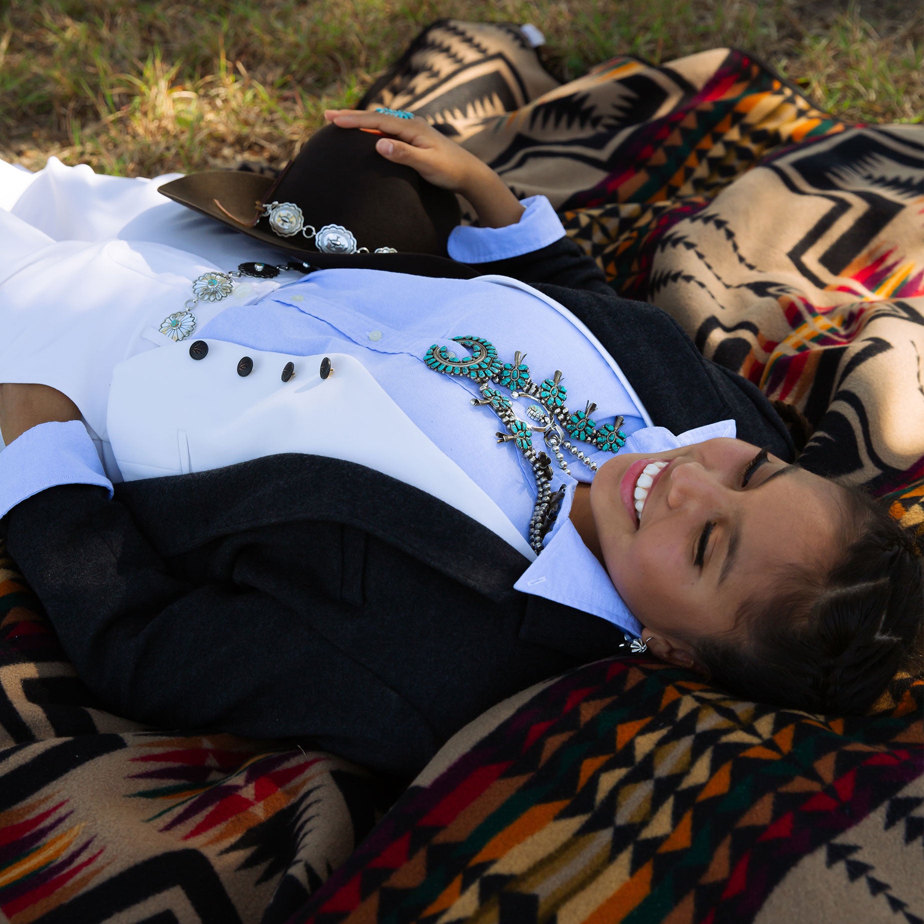 Person lying on a pendleton blanket with a cowboy hat and navajo jewelry.