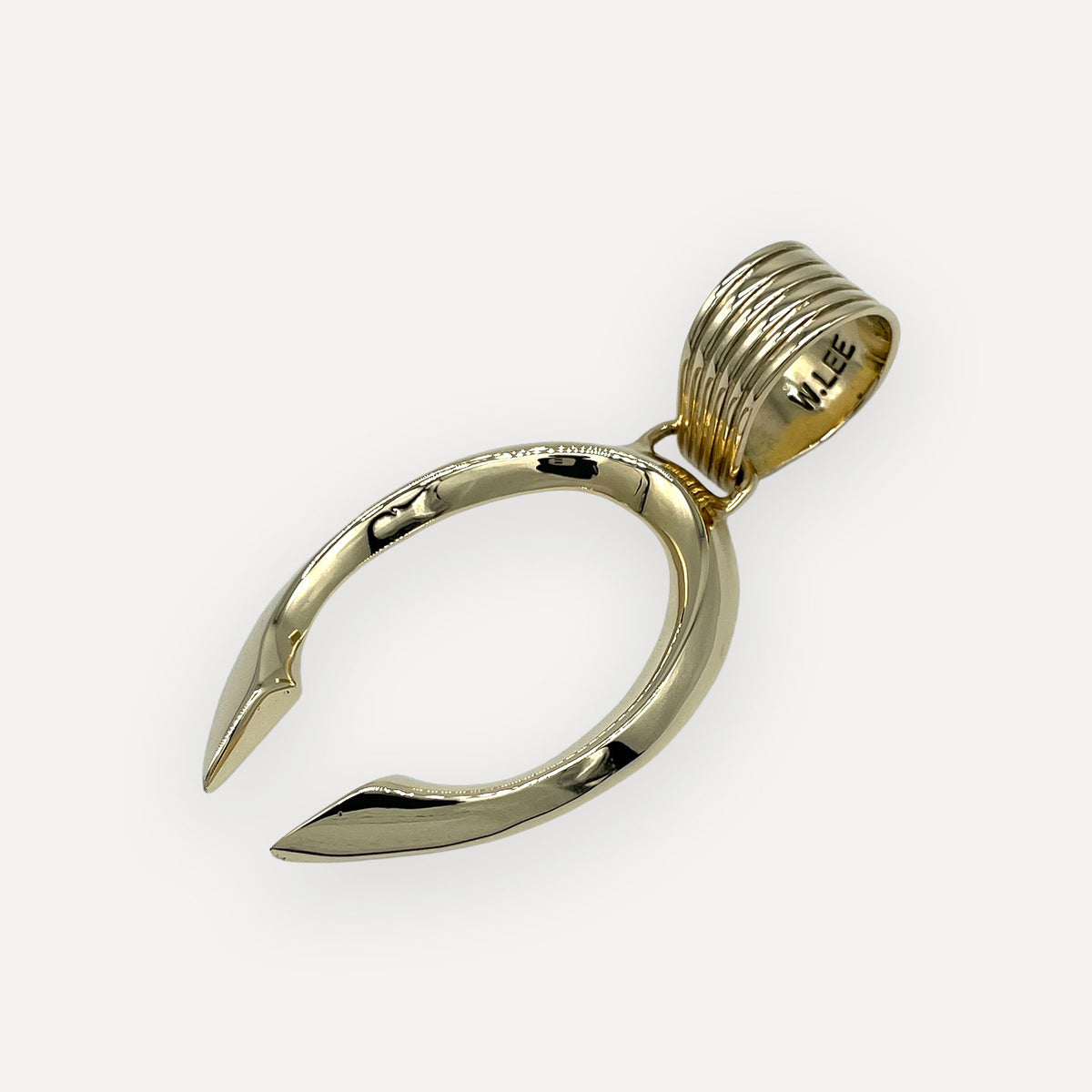Side view of an 18 karat gold naja pendant showing the W. Lee hallmark inside the fluted bail