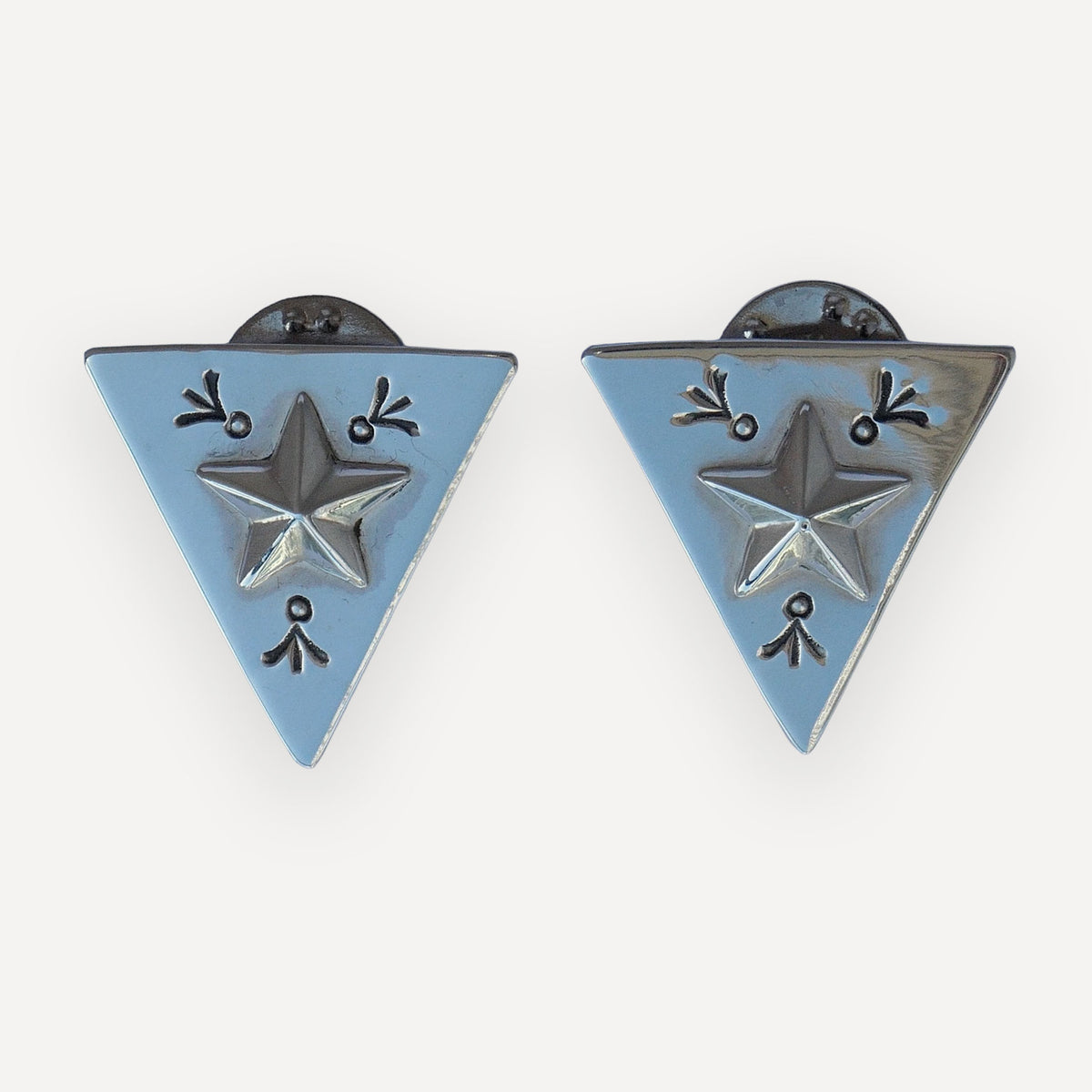 Pair of triangular sterling silver collar tips with a raised lone star and hand-stamped navajo accents on a white background