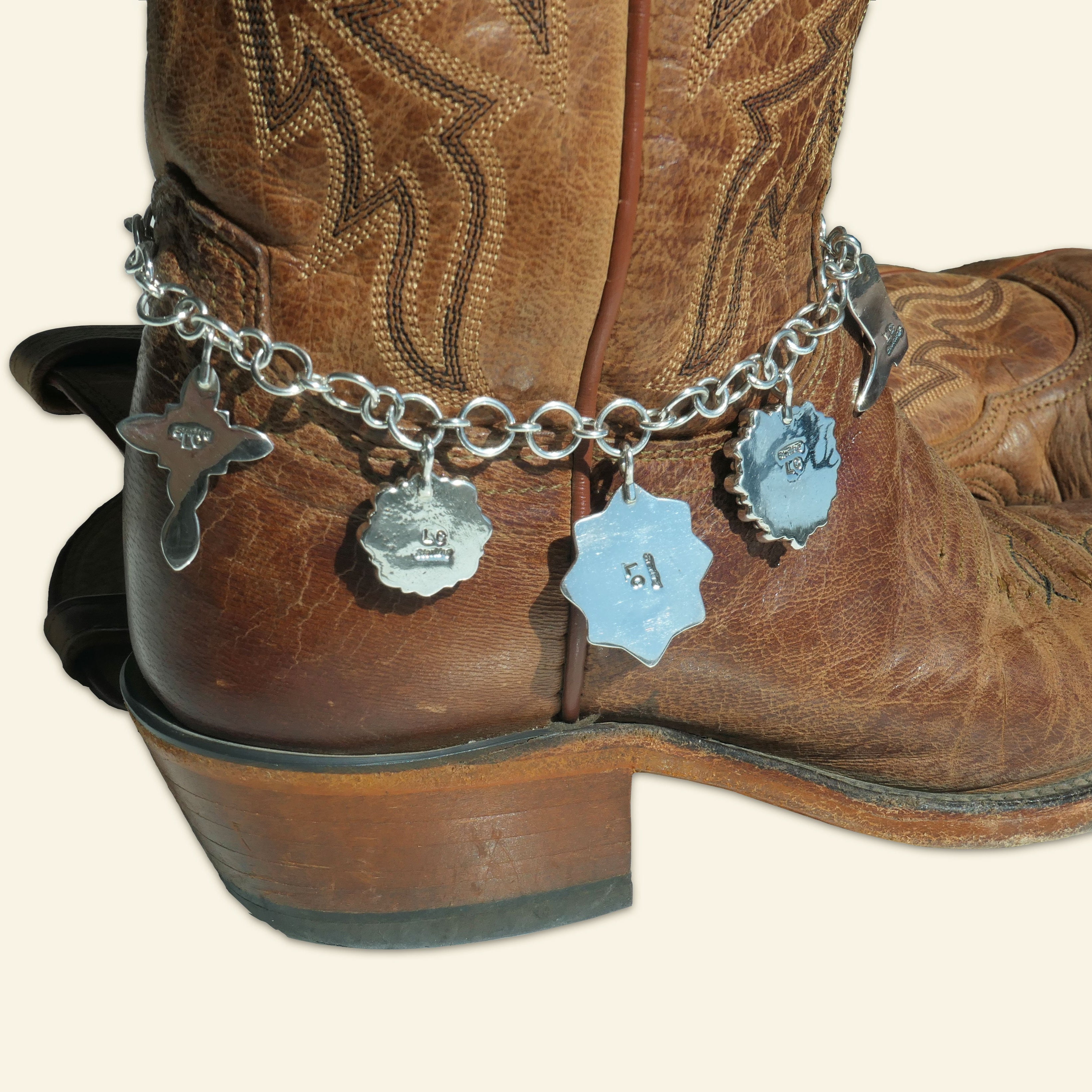 Brown leather cowboy boot featuring a silver boot jewelry chain wrapped around the ankle, adorned with Western-style charms and Lee Charley Hallmark 