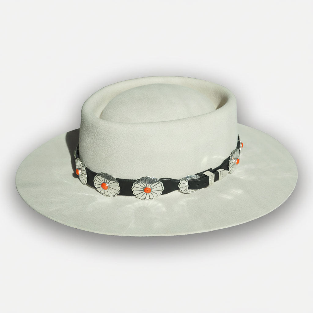 White fedora hat with black leather hat band and orange spiny oyster stones on white background. 