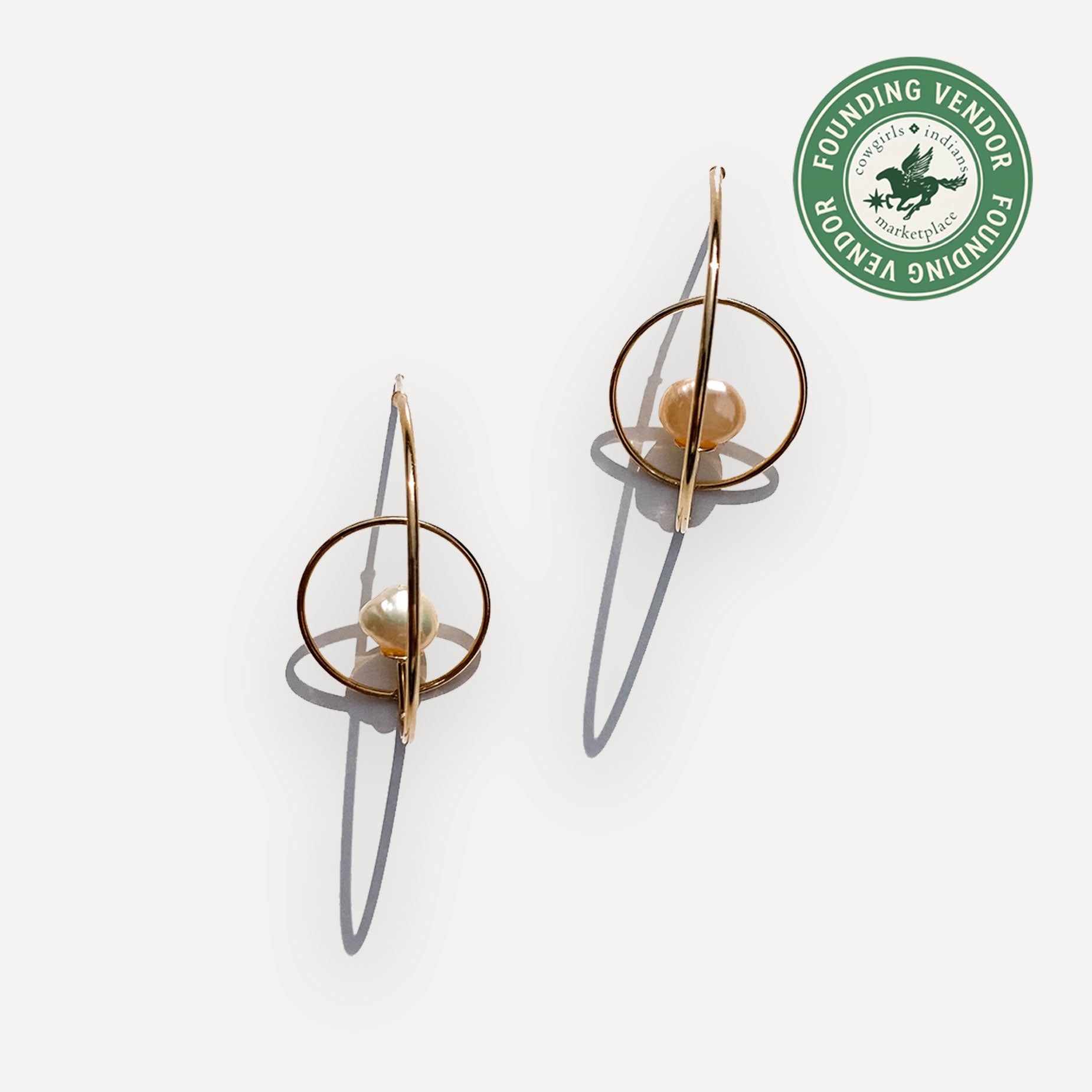 Gold hoop earrings with a pearl center on a white background, featuring a Founding Vendor badge.