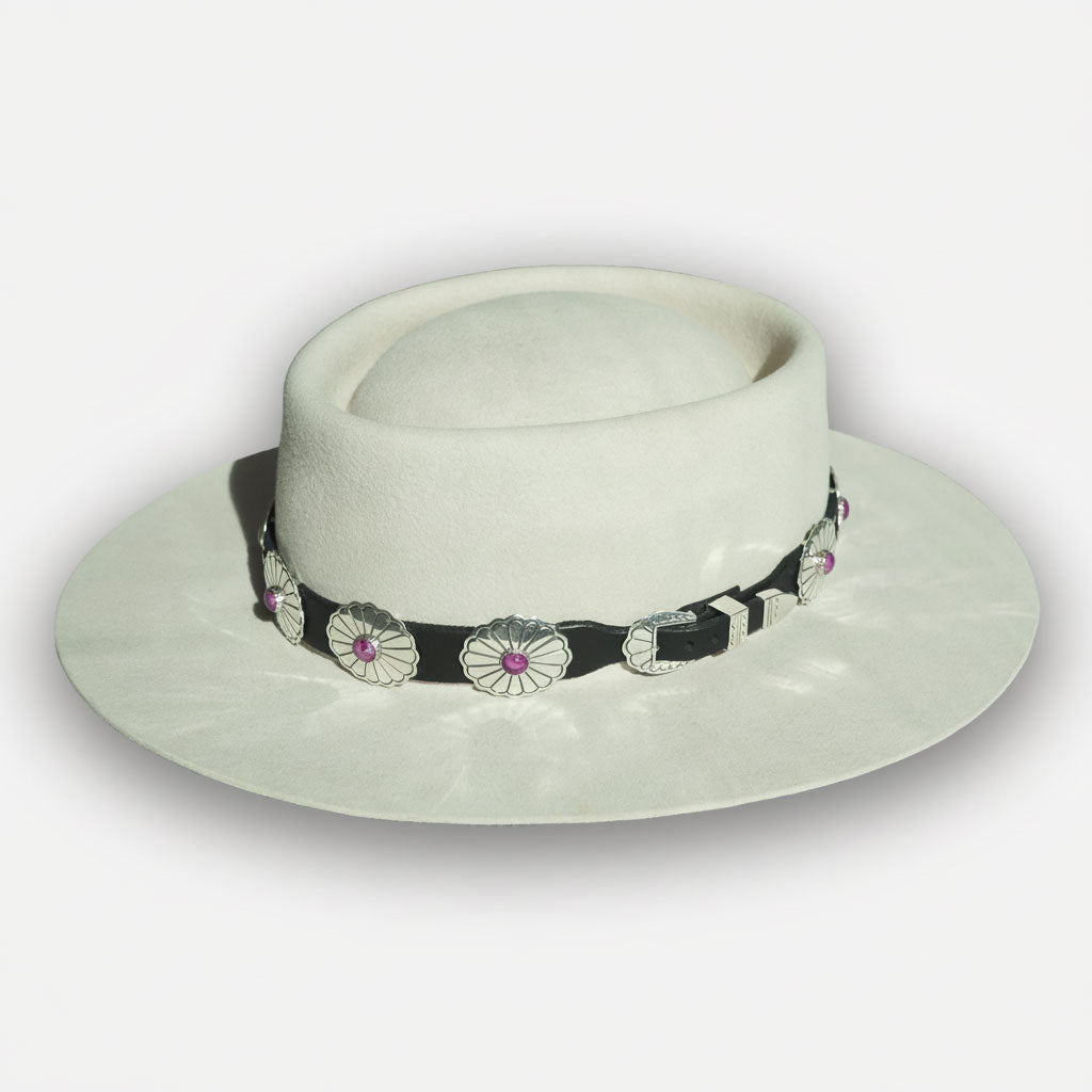 Flat brimmed western hat with black leather and purple spiny oyster hat band on white background. 