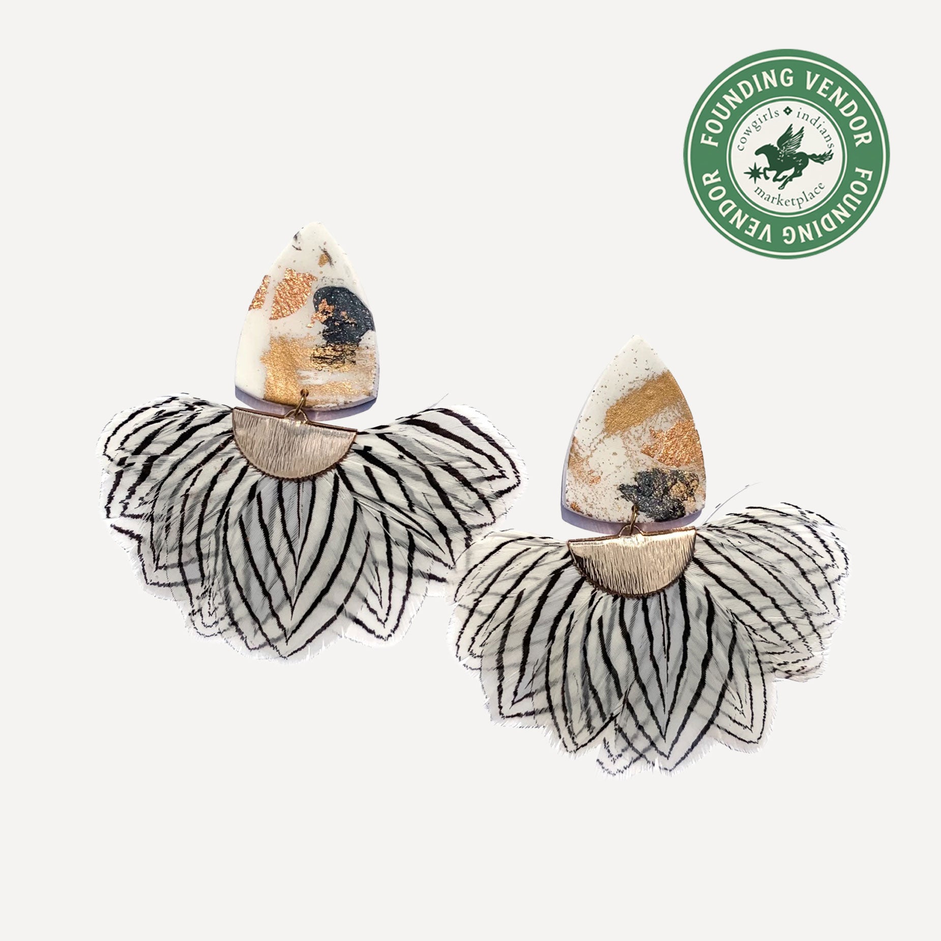 Pair of earrings with clay and guinea feathers on a white background, featuring a Founding Vendor logo.