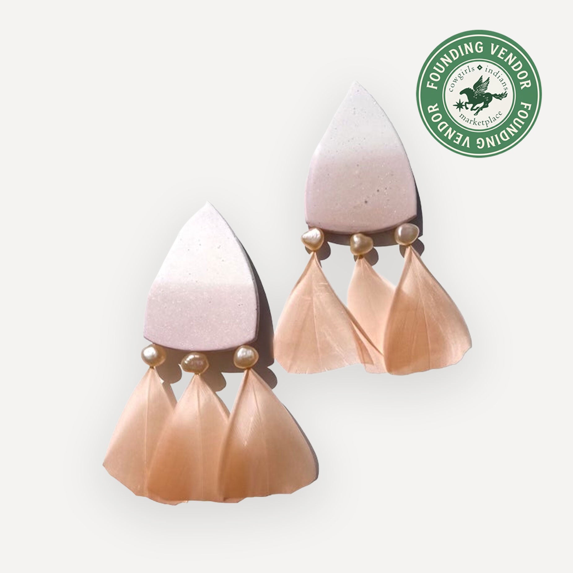 Pair of pink and beige earrings on white background

